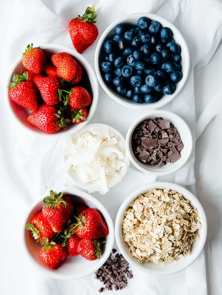 Bowls of strawberries, blueberries, oats, coconut, and chocolate for popsicles