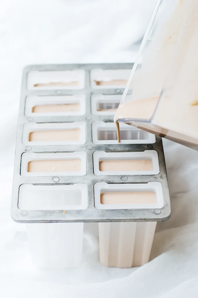 Pouring chocolate smoothie base into popsicle molds