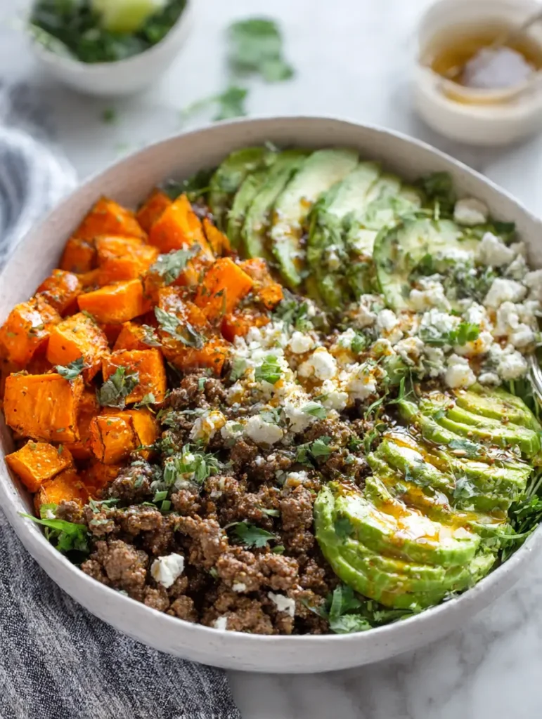 Hot Honey Ground Beef Bowl with sweet potatoes, cottage cheese, and avocado on a white table